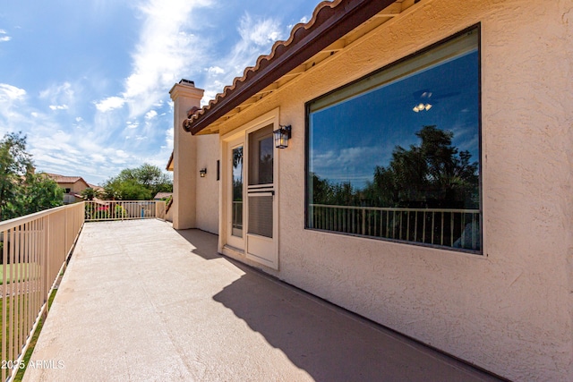 view of property exterior with stucco siding, a tiled roof, and a balcony