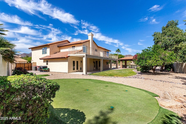 rear view of property featuring a tiled roof, french doors, a patio area, a fenced backyard, and stucco siding