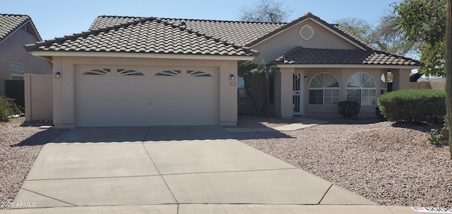 view of front of property featuring stucco siding, an attached garage, driveway, and a tiled roof