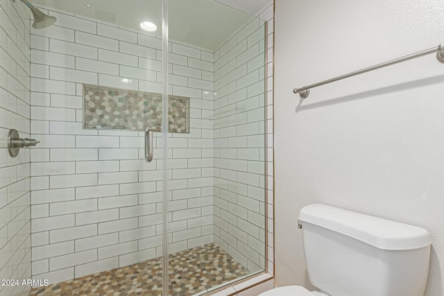 bathroom featuring toilet and a shower with door