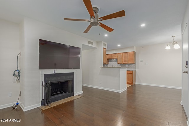 unfurnished living room with ceiling fan with notable chandelier and dark hardwood / wood-style floors