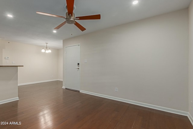 empty room with ceiling fan with notable chandelier and dark hardwood / wood-style floors