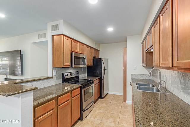 kitchen with decorative backsplash, dark stone countertops, light tile patterned flooring, stainless steel appliances, and sink