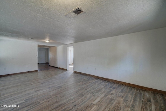 spare room with a textured ceiling and hardwood / wood-style flooring