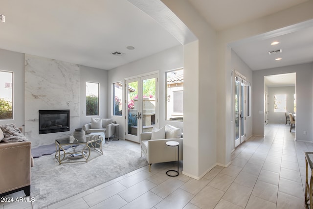 living room with french doors, light tile patterned flooring, and a fireplace