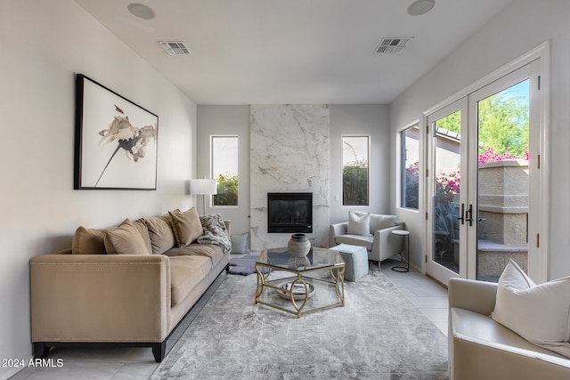 living room featuring french doors, a premium fireplace, and light tile patterned floors