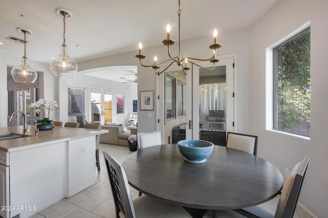 dining area with light tile patterned floors, sink, and ceiling fan with notable chandelier