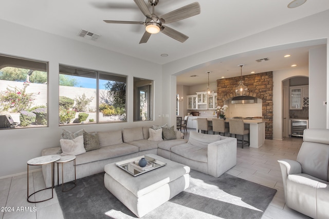 living room featuring wine cooler and ceiling fan with notable chandelier