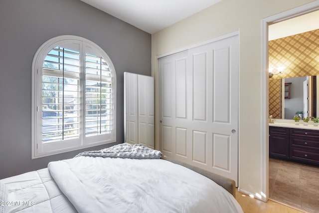 bedroom with connected bathroom, a closet, and light wood-type flooring