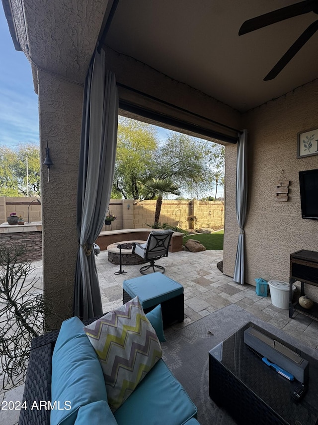 view of patio with ceiling fan and an outdoor living space with a fire pit