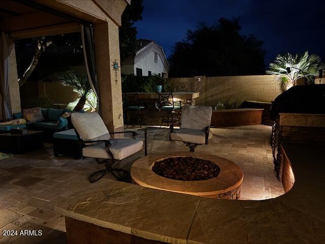 patio at night featuring an outdoor living space with a fire pit