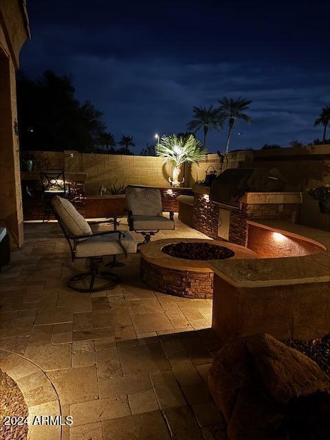 patio at twilight featuring an outdoor kitchen and a fire pit