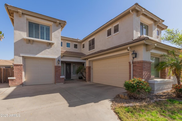 view of front of property with a garage, brick siding, driveway, and stucco siding