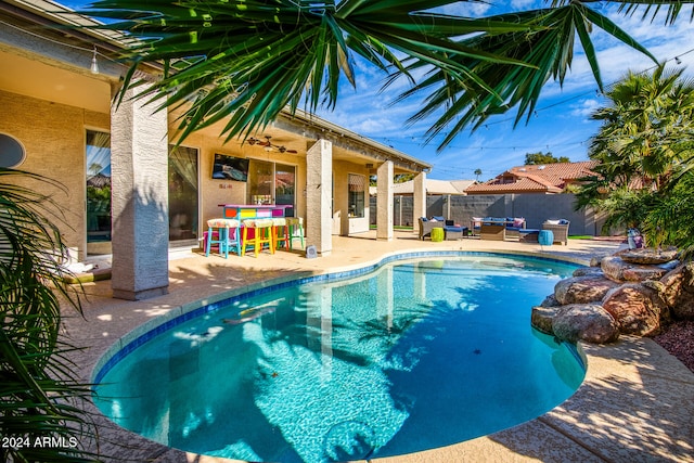 view of swimming pool with a bar, ceiling fan, and a patio area