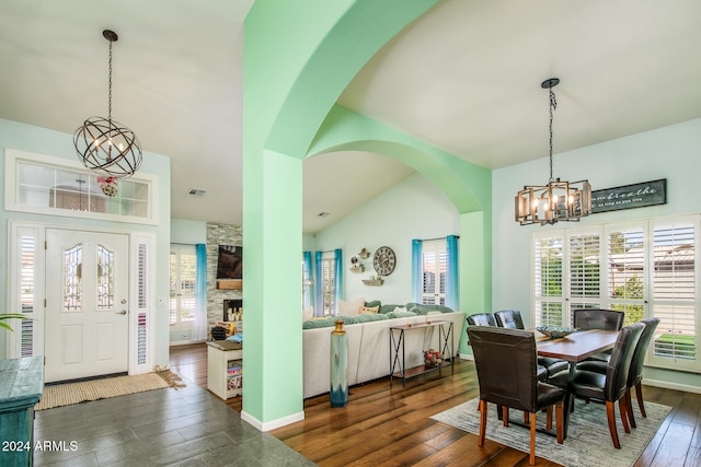 dining room featuring a notable chandelier, dark wood-type flooring, and vaulted ceiling