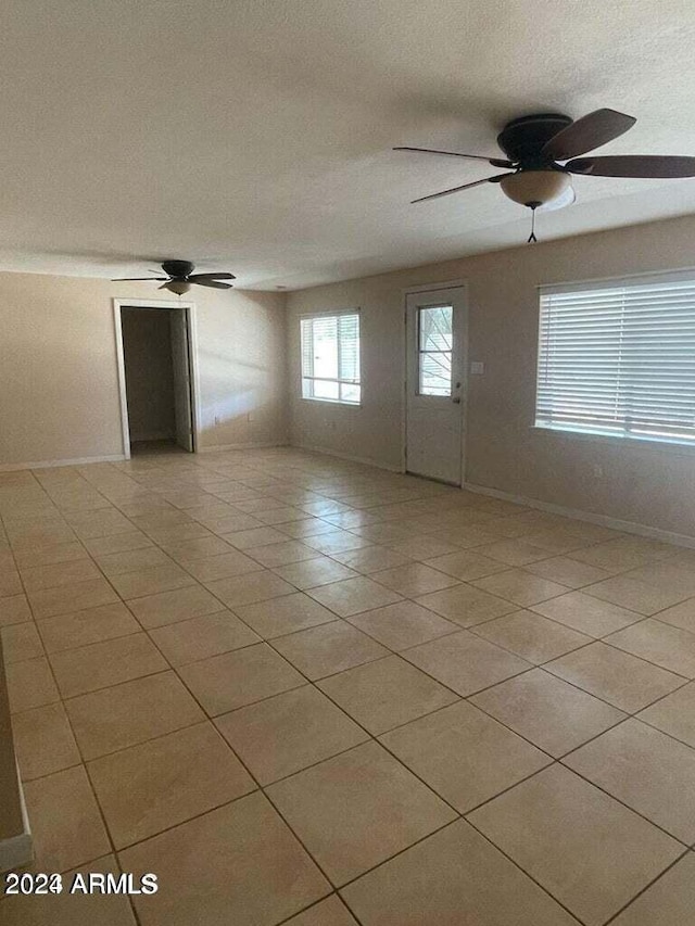 unfurnished room featuring ceiling fan, a textured ceiling, baseboards, and light tile patterned floors