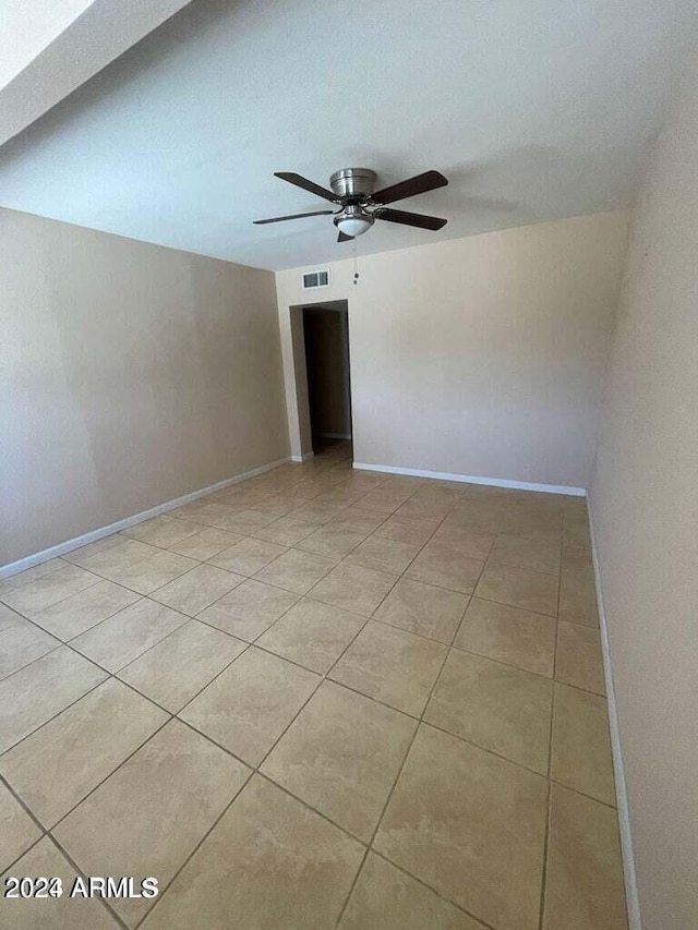 unfurnished room with baseboards, light tile patterned flooring, visible vents, and a ceiling fan