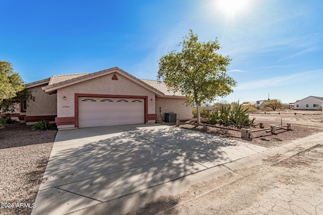 ranch-style house with central air condition unit and a garage