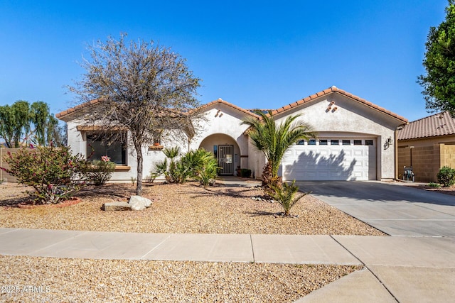 mediterranean / spanish-style home with an attached garage, a tile roof, concrete driveway, and stucco siding