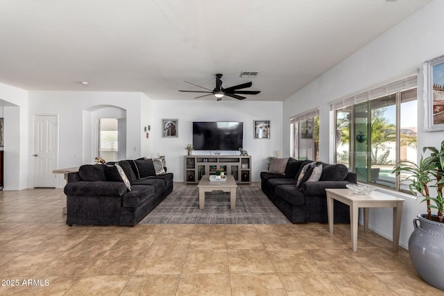 living area featuring ceiling fan, visible vents, arched walkways, and tile patterned flooring