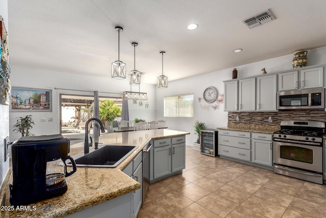 kitchen featuring stainless steel appliances, a sink, visible vents, gray cabinets, and decorative backsplash