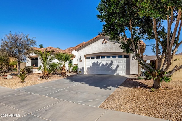 mediterranean / spanish house with a garage, concrete driveway, a tile roof, and stucco siding