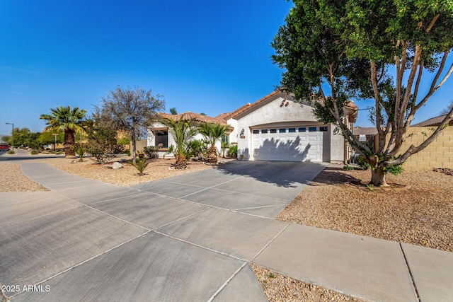 mediterranean / spanish house with a garage, a tile roof, driveway, and stucco siding