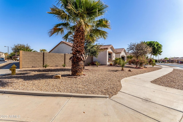 view of front of property with a tile roof, fence, and stucco siding