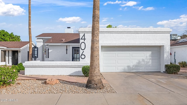 view of front of property with driveway, a chimney, stucco siding, a garage, and central air condition unit