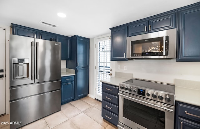 kitchen featuring visible vents, high quality appliances, blue cabinetry, light countertops, and light tile patterned floors