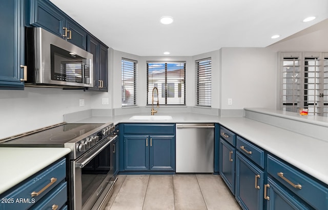 kitchen with a sink, stainless steel appliances, blue cabinets, and light countertops