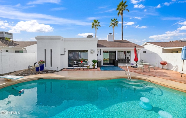 back of house featuring a fenced in pool, fence, a chimney, and a patio area