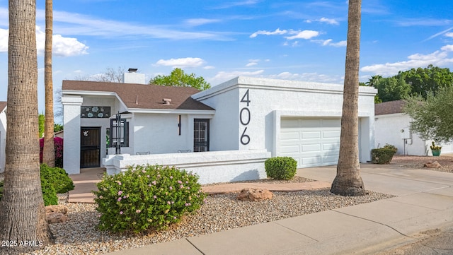 view of front of property featuring a fenced front yard, stucco siding, a chimney, a garage, and driveway