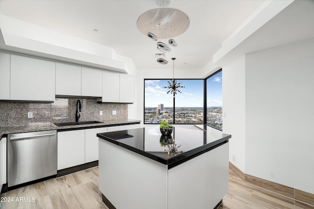 kitchen with stainless steel dishwasher, a center island, white cabinets, and sink