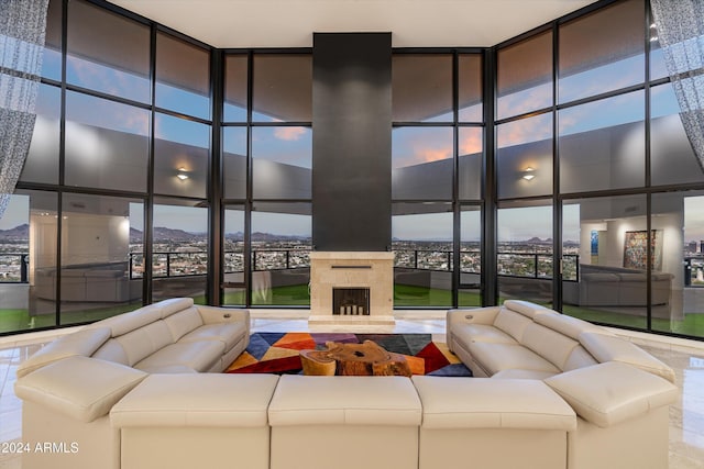 tiled living room with a large fireplace, a wall of windows, and a towering ceiling