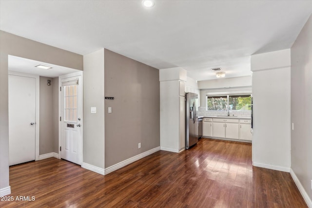 interior space featuring appliances with stainless steel finishes, dark hardwood / wood-style floors, white cabinetry, sink, and decorative backsplash