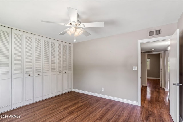 unfurnished bedroom with dark hardwood / wood-style flooring, a closet, and ceiling fan