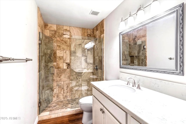 bathroom featuring vanity, hardwood / wood-style floors, a shower with shower door, and toilet