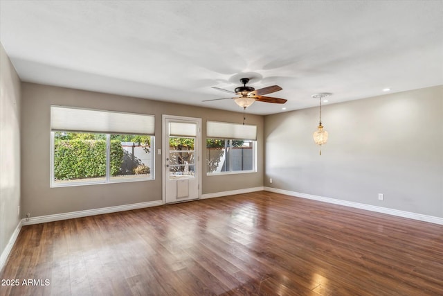 unfurnished room with ceiling fan, a healthy amount of sunlight, and dark hardwood / wood-style flooring