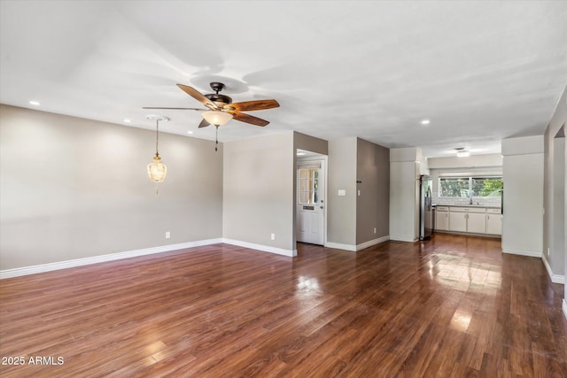 unfurnished living room featuring ceiling fan and dark hardwood / wood-style flooring