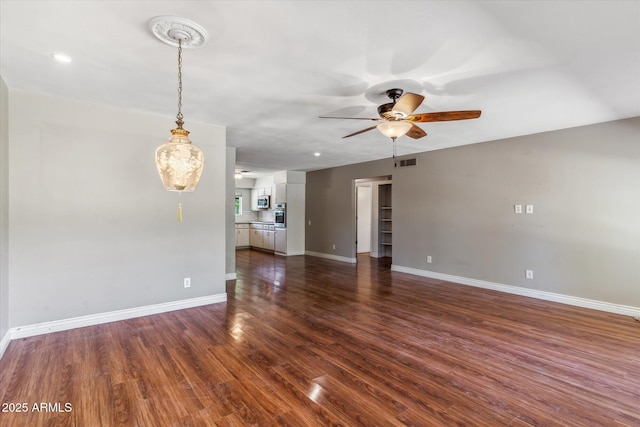 unfurnished living room with dark hardwood / wood-style floors and ceiling fan