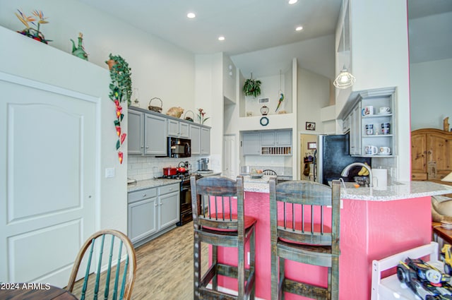 kitchen featuring light hardwood / wood-style flooring, stainless steel appliances, a high ceiling, and gray cabinets