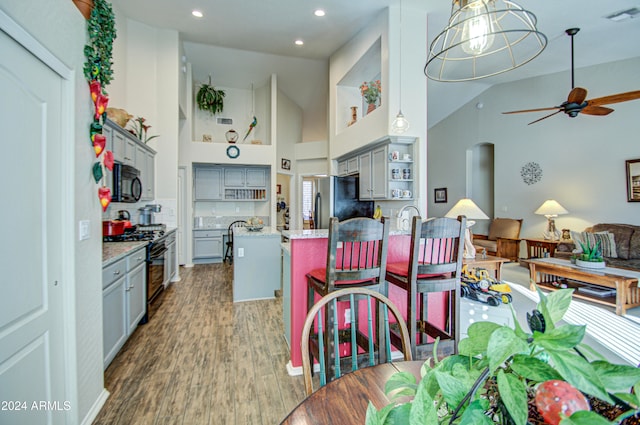 dining space with ceiling fan, high vaulted ceiling, and dark hardwood / wood-style flooring