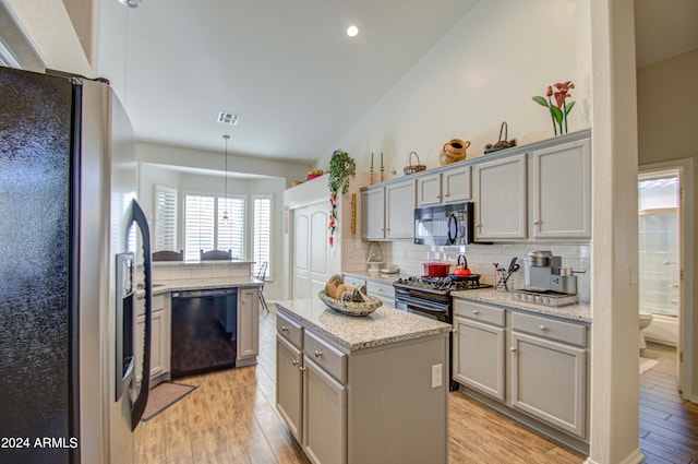 kitchen featuring light hardwood / wood-style floors, black appliances, pendant lighting, and a kitchen island