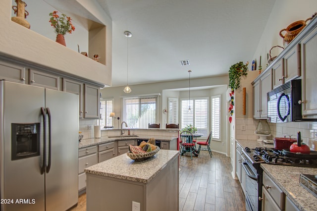 kitchen featuring appliances with stainless steel finishes, decorative light fixtures, plenty of natural light, and a kitchen island