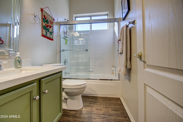 full bathroom with vanity, toilet, hardwood / wood-style flooring, and bath / shower combo with glass door