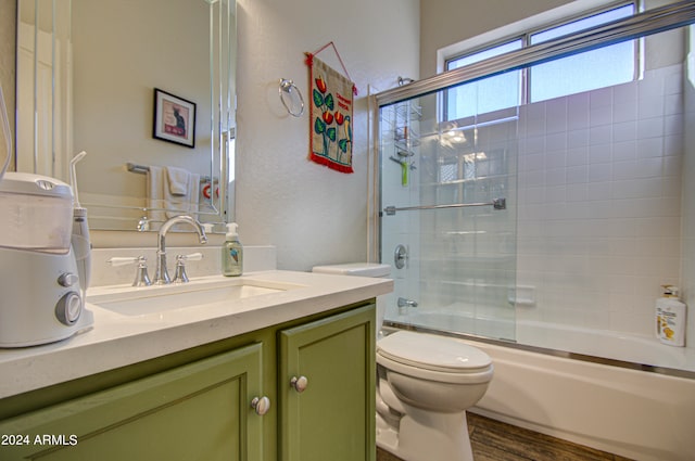 full bathroom with vanity, toilet, wood-type flooring, and shower / bath combination with glass door