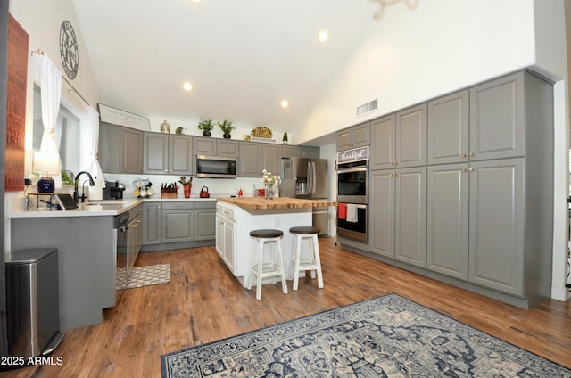 kitchen featuring visible vents, gray cabinetry, a breakfast bar, a sink, and stainless steel appliances