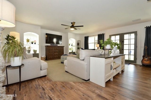 living area featuring arched walkways, visible vents, french doors, and wood finished floors