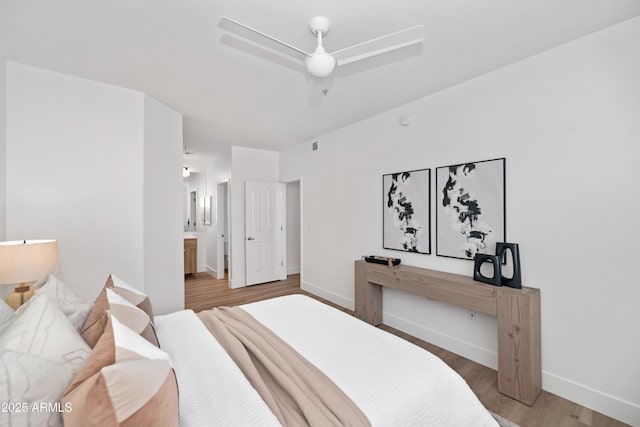 bedroom with ceiling fan, connected bathroom, baseboards, and wood finished floors